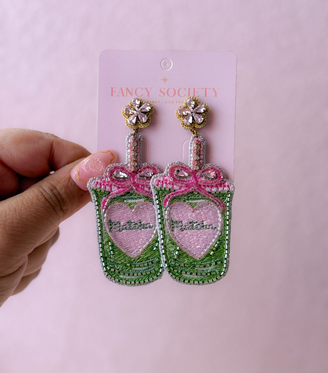 beaded matcha earrings, with a pink bow. Placed on a fancy society card